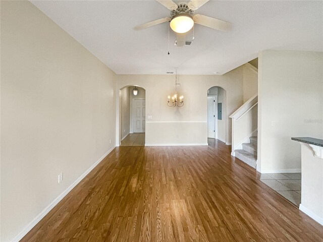 unfurnished living room featuring ceiling fan with notable chandelier and hardwood / wood-style floors