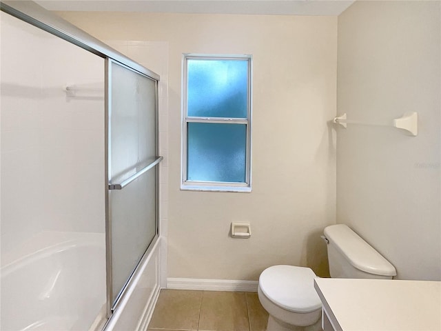 full bathroom with toilet, tile patterned floors, bath / shower combo with glass door, vanity, and a wealth of natural light