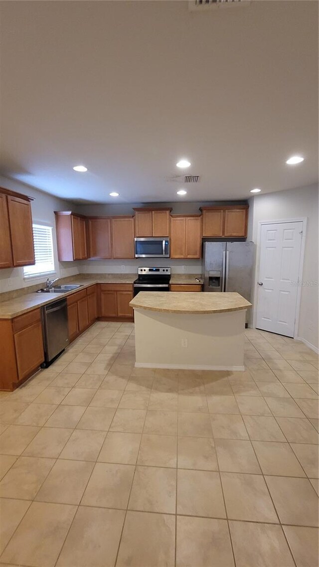 kitchen with appliances with stainless steel finishes, light tile patterned flooring, and a center island