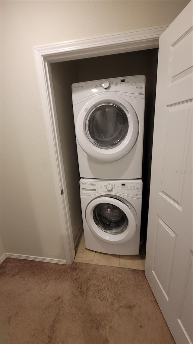 laundry area featuring light tile patterned floors and stacked washer / drying machine