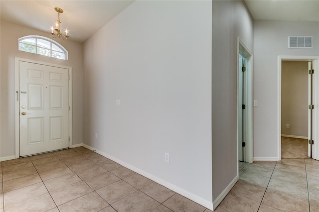 tiled foyer entrance featuring an inviting chandelier