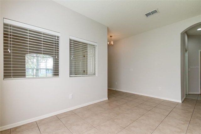 empty room featuring tile patterned floors and an inviting chandelier