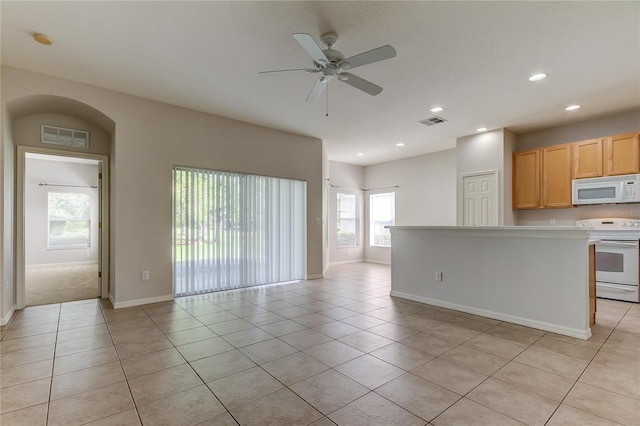 kitchen with light tile patterned floors, white appliances, ceiling fan, and light brown cabinetry