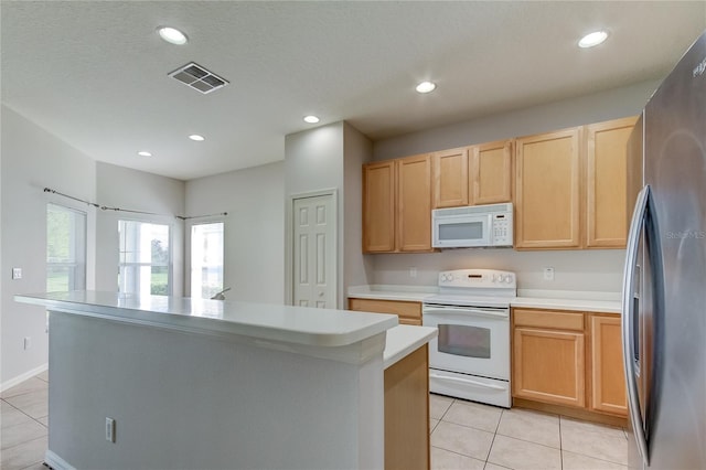 kitchen with light tile patterned flooring, light brown cabinets, white appliances, and a kitchen island