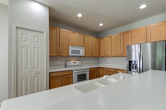 kitchen with white appliances, sink, and light brown cabinets