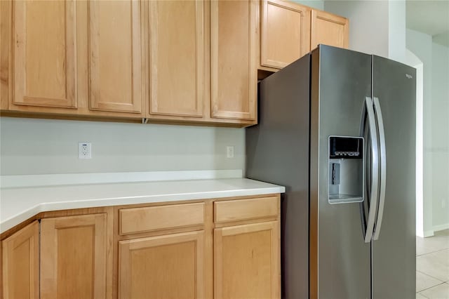 kitchen featuring stainless steel fridge, light tile patterned flooring, and light brown cabinets