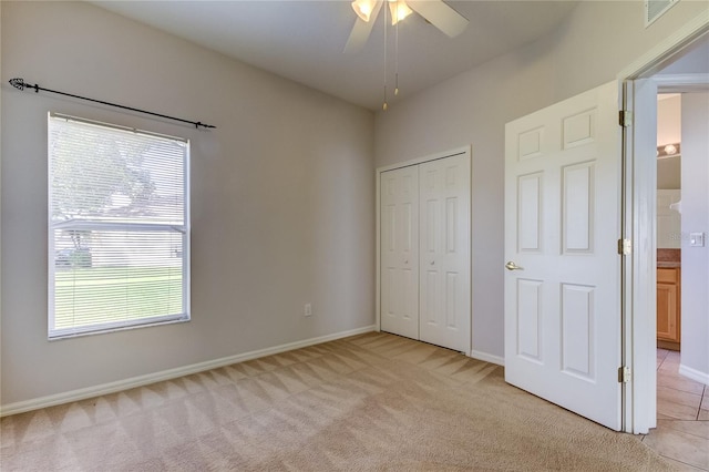 unfurnished bedroom featuring ceiling fan, light colored carpet, and a closet