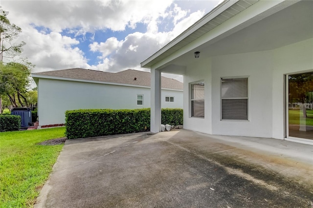 view of side of home featuring a patio area, central AC unit, and a lawn