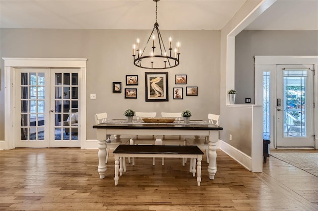 dining room featuring a notable chandelier, plenty of natural light, and wood-type flooring