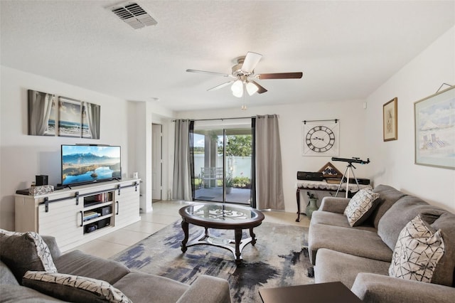 tiled living room featuring ceiling fan and a textured ceiling