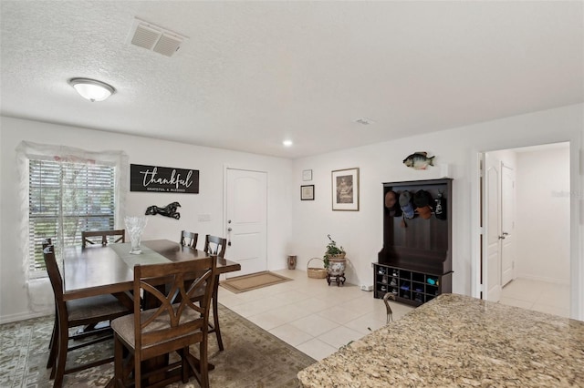 dining area featuring a textured ceiling and light tile patterned floors