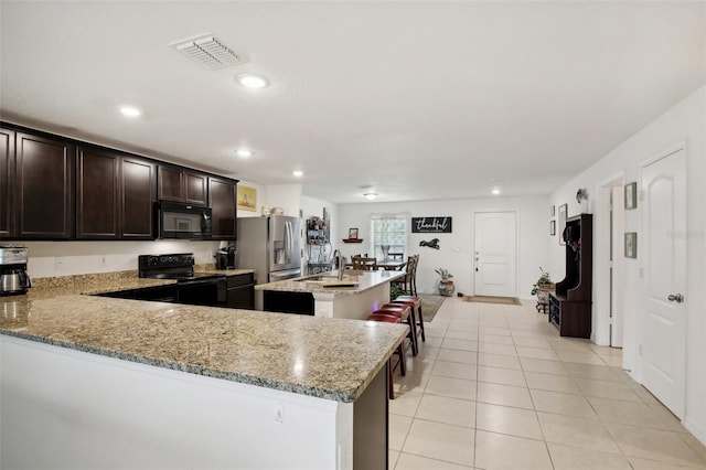 kitchen with light tile patterned floors, sink, light stone counters, and black appliances