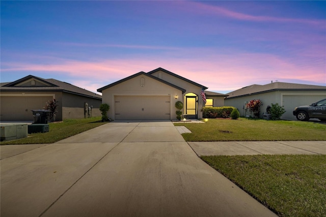 ranch-style home featuring a garage and a lawn