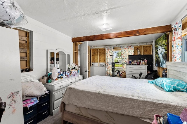 carpeted bedroom featuring a textured ceiling and beamed ceiling