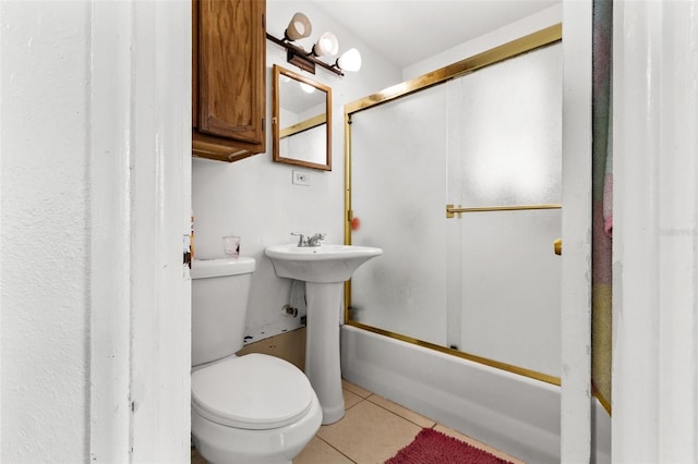 bathroom featuring toilet, bath / shower combo with glass door, and tile patterned flooring