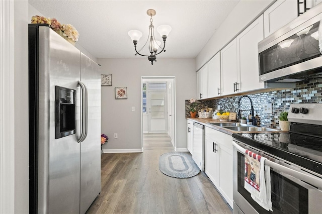 kitchen with tasteful backsplash, appliances with stainless steel finishes, sink, white cabinets, and hardwood / wood-style floors