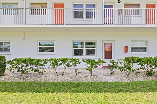 entrance to property featuring a lawn and a balcony