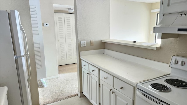 kitchen featuring light carpet, premium range hood, white cabinets, stove, and white fridge