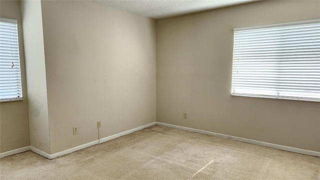 carpeted spare room with a textured ceiling and a wealth of natural light