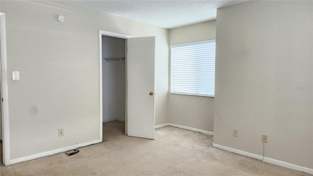 unfurnished bedroom featuring a textured ceiling, light colored carpet, and a closet