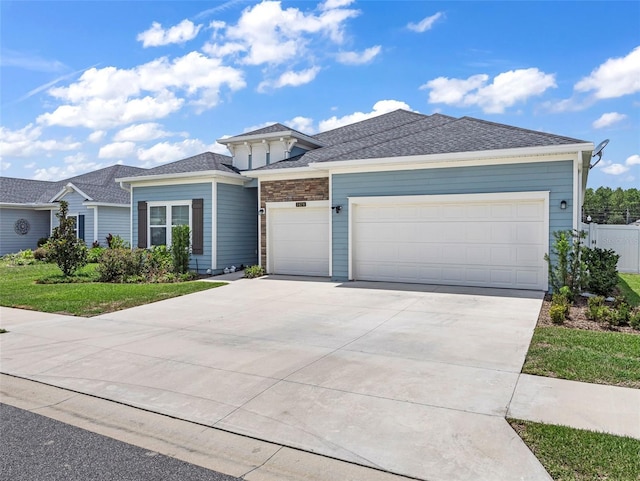 view of front facade featuring a garage, driveway, stone siding, and fence