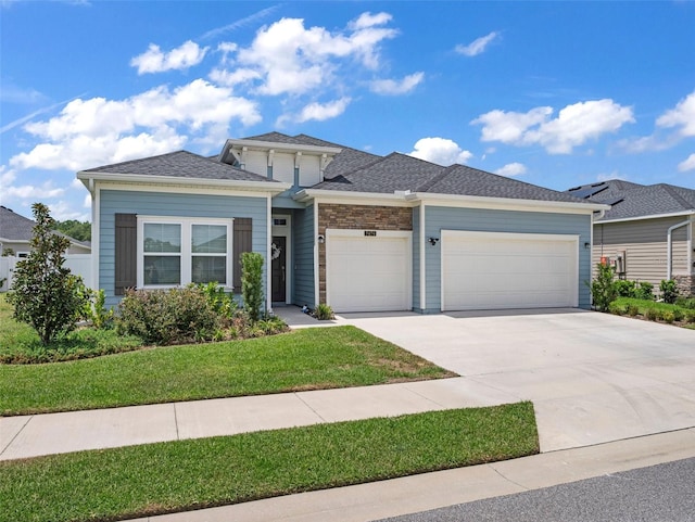 prairie-style house with a front yard, roof with shingles, driveway, and an attached garage