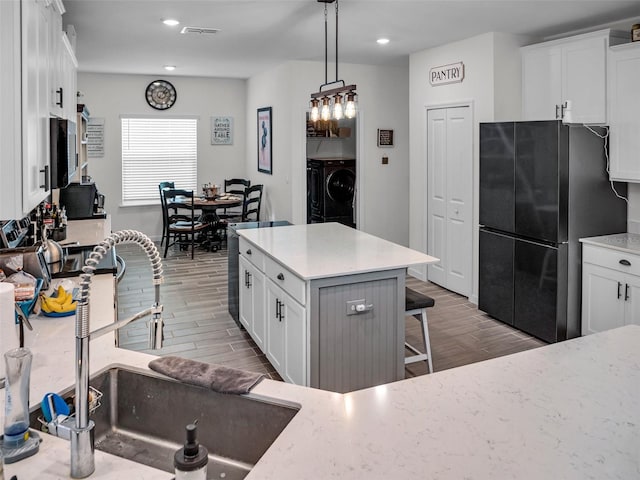 kitchen featuring freestanding refrigerator, a sink, washer and clothes dryer, and wood tiled floor