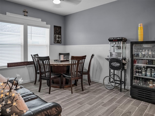 dining space featuring wood finish floors, wainscoting, and a ceiling fan