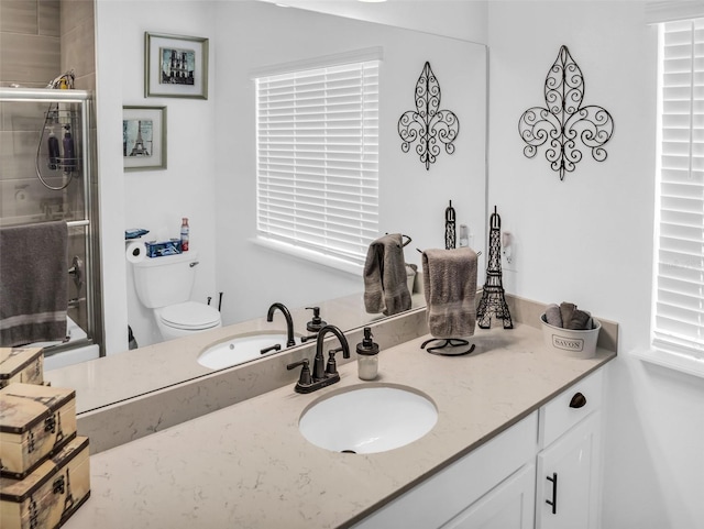 bathroom with toilet, a tile shower, and vanity