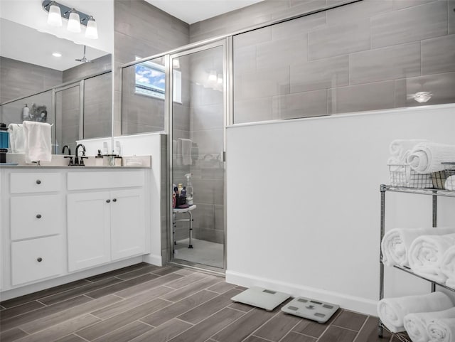 bathroom with wood finish floors, a shower stall, vanity, and baseboards