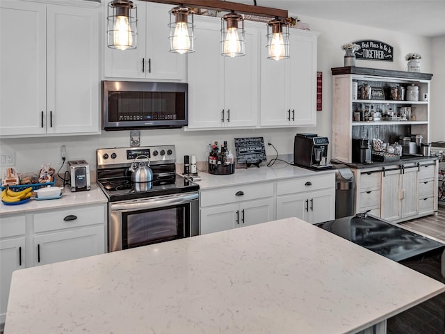 kitchen with wood finished floors, white cabinets, appliances with stainless steel finishes, light stone countertops, and pendant lighting