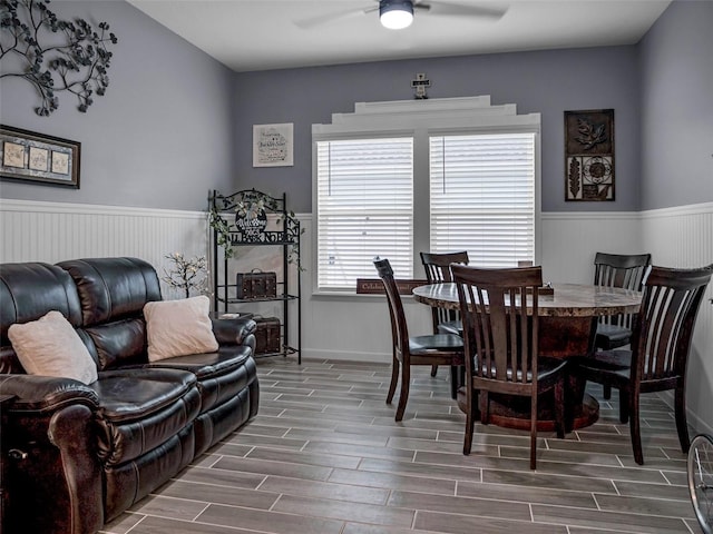 dining area with a wainscoted wall, ceiling fan, and wood tiled floor