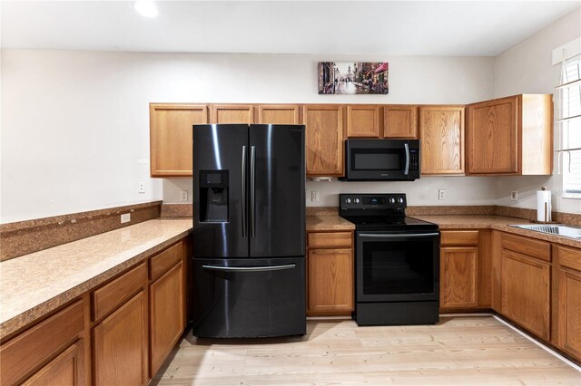 kitchen with black appliances, sink, and light hardwood / wood-style floors