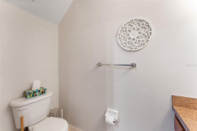 bathroom featuring toilet, vanity, and lofted ceiling