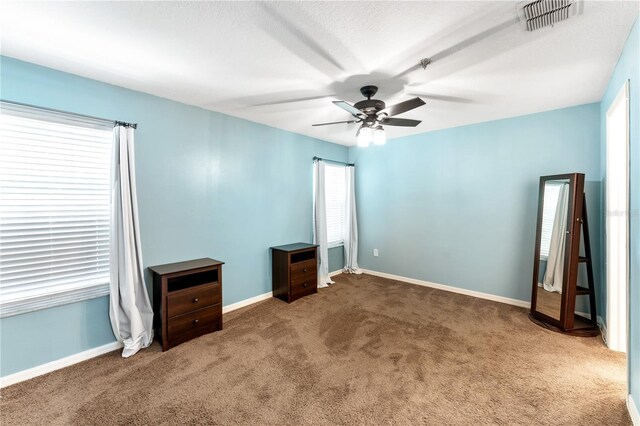 spare room featuring ceiling fan and dark carpet