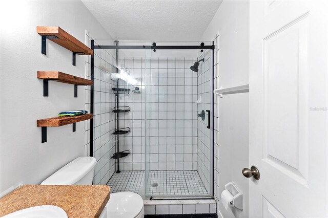 bathroom with a textured ceiling, a shower with door, toilet, and vanity