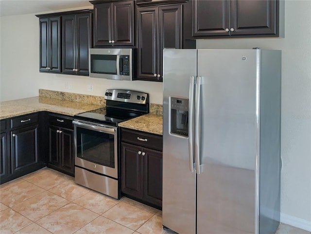 kitchen featuring light tile patterned floors, light stone counters, and stainless steel appliances