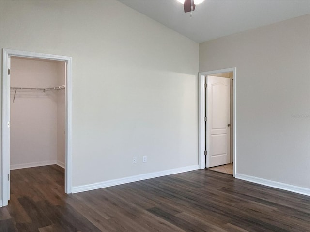 unfurnished bedroom featuring ceiling fan, dark wood-style flooring, baseboards, a spacious closet, and a closet