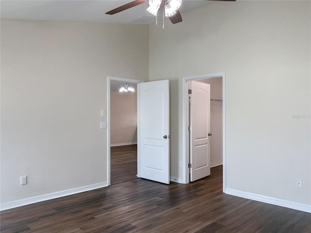 unfurnished bedroom featuring ceiling fan, dark wood-style flooring, a walk in closet, and baseboards