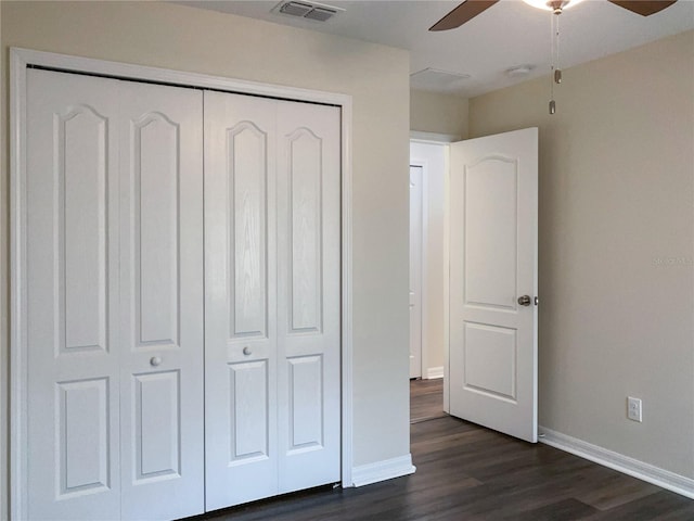 unfurnished bedroom with baseboards, visible vents, ceiling fan, dark wood-style flooring, and a closet