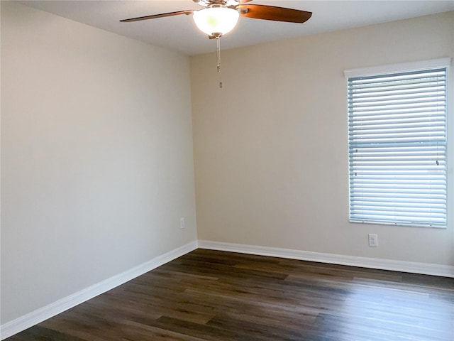 spare room with a ceiling fan, plenty of natural light, baseboards, and dark wood-type flooring