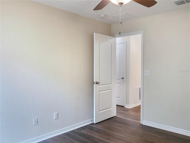 empty room featuring visible vents, dark wood finished floors, baseboards, and ceiling fan