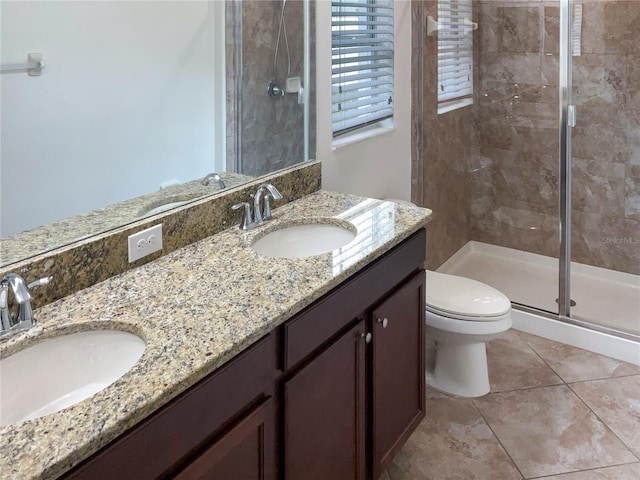 bathroom with double vanity, a stall shower, a sink, and toilet