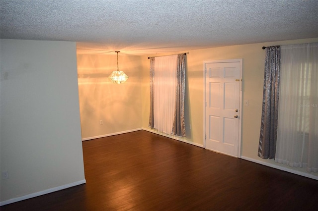 unfurnished room with dark hardwood / wood-style flooring and a textured ceiling