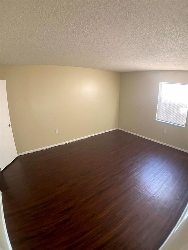 spare room with dark hardwood / wood-style floors and a textured ceiling