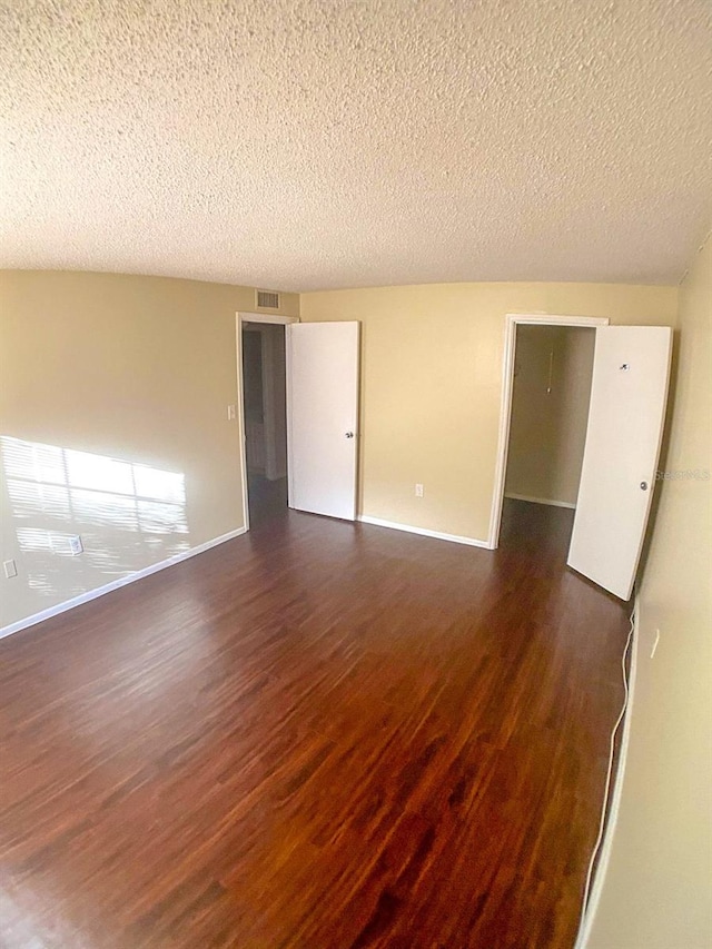 unfurnished room with wood-type flooring and a textured ceiling