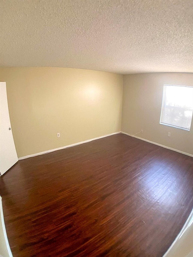 empty room featuring a textured ceiling and dark hardwood / wood-style floors