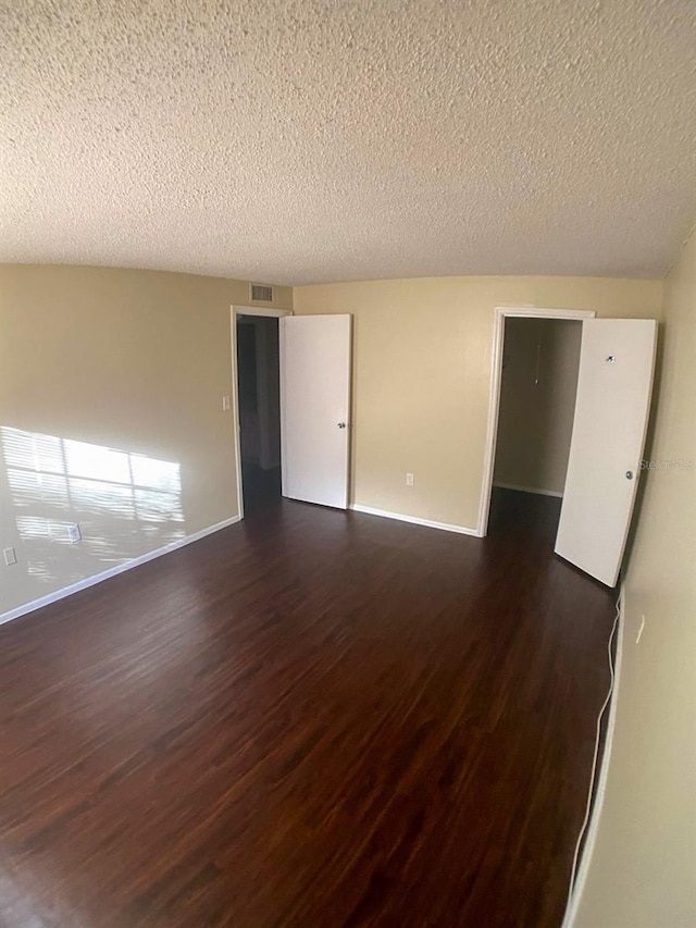 unfurnished room with dark hardwood / wood-style flooring and a textured ceiling