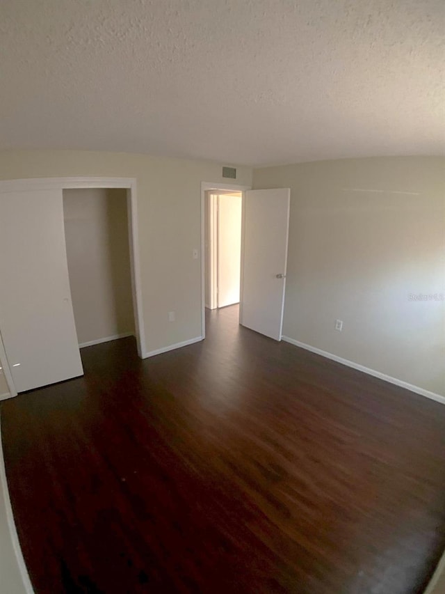 empty room featuring a textured ceiling and dark hardwood / wood-style flooring