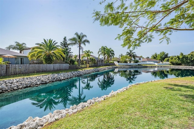 view of swimming pool with a lawn, a water view, and fence